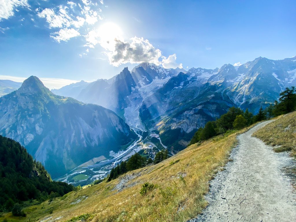 green grass field near mountain under blue sky during daytime