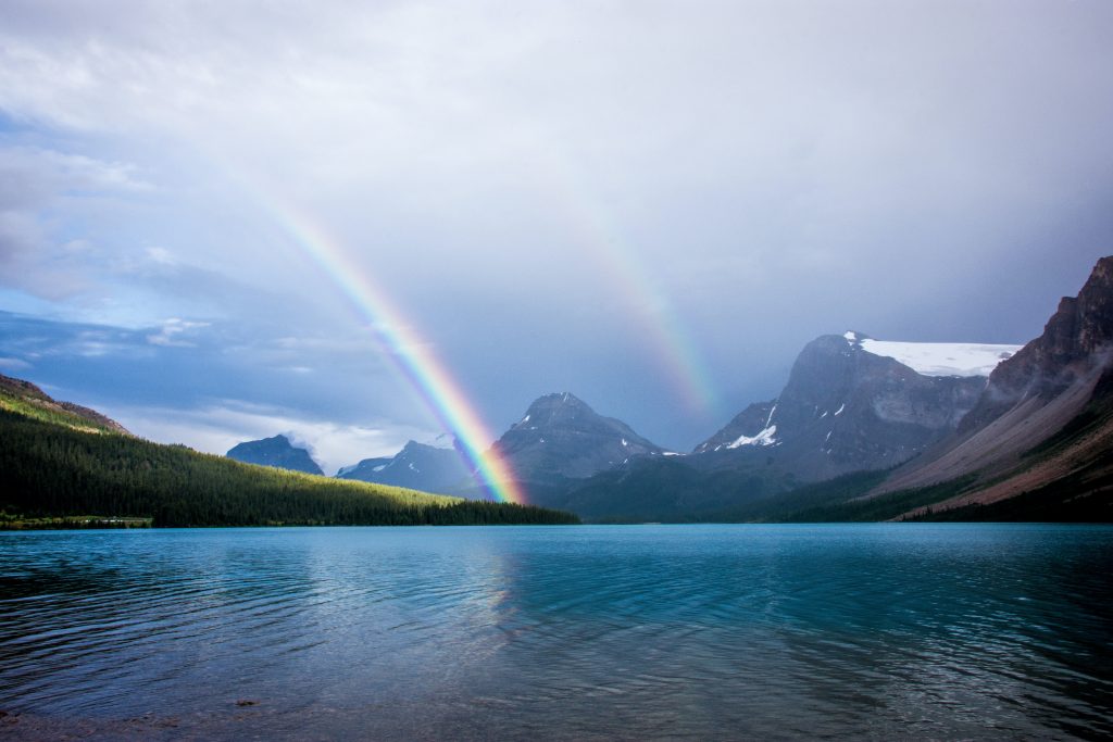 blue lake and rainbow under nimbus clouds