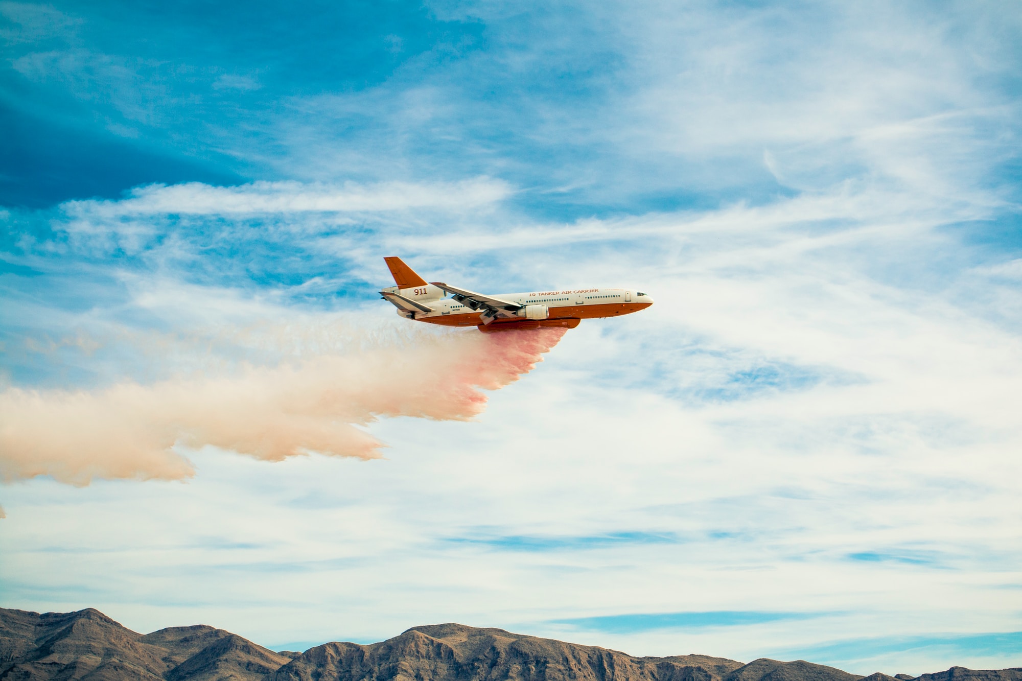 white plane spreading pink smoke